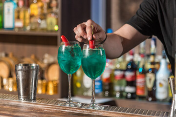 Bartender prepares two glasses with cocktails