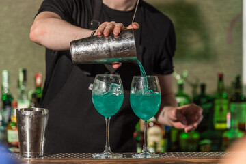 Bartender prepares two glasses with cocktails