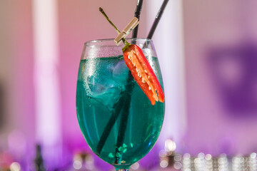 Glass with blue color cocktail with chili pepper