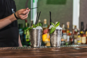 The barman prepares an alcoholic cocktail with fresh mint