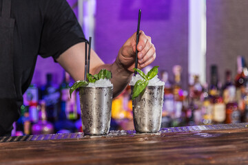 The barman prepares an alcoholic cocktail with fresh mint