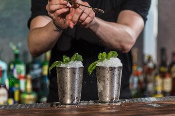 The barman prepares an alcoholic cocktail with fresh mint