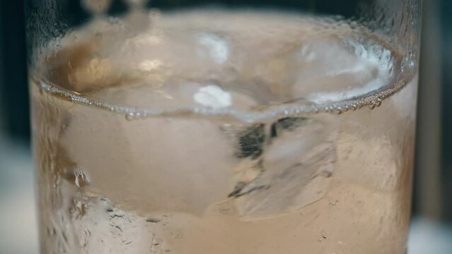 Mixing ice in a glass with a carbonated drink