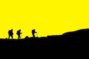 Silhouette escursionisti che camminano in montagna cielo giallo
