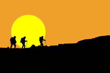 Escursionisti silhouette in ombra che camminano in montagna sul sentiero con cielo arancione e sole giallo