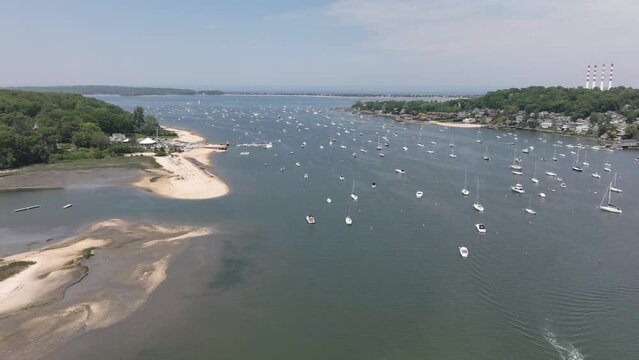 An aerial time lapse over the Northport Marina on Long island, NY. It is a sunny day with many anchored boats. The drone camera dolly in high above the marina as other boats cruise by quickly.