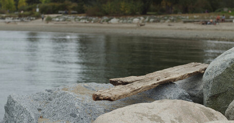 Wooden plank on rocks and boulders with a blurred beach background.
