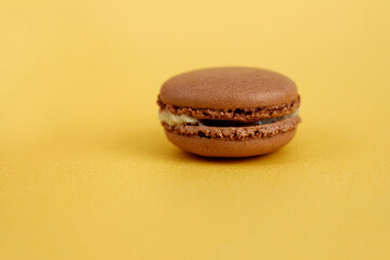 Chocolate macaron, french dessert made from egg whites, on a golden background