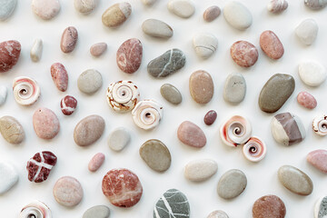 Top view close up pebbles, sea stones, shells on white don as summer background. Natural stone natural shade. Minimal style flat lay, concept of calm, peace, meditation. summer pattern.