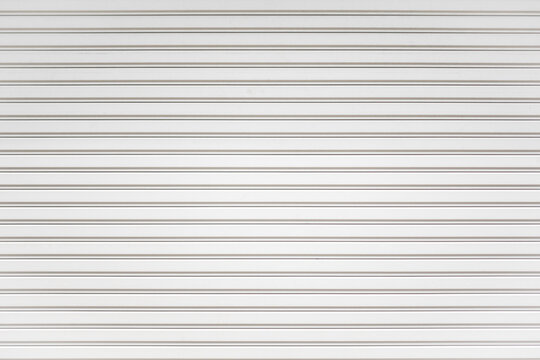 White metal roller shutter door background. Steel stripe horizontal lines of iron foldable metal sheet texture. Empty front warehouse garage abstract pattern.
