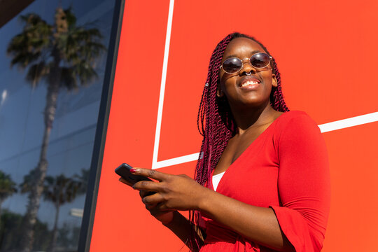 Cheerful black woman using smartphone