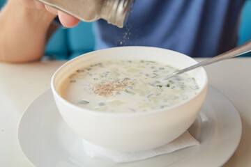 He eats soup okroshka from  round white plate