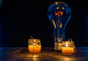 Glowing lamp, tungsten light bulb lit on black background,  close up shot, on wood table,  idea...