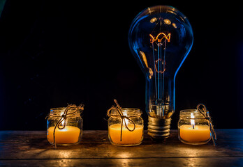 Glowing lamp, tungsten light bulb lit on black background,  close up shot, on wood table,  idea...