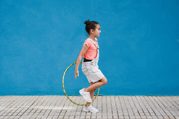 Cute little girl with hula hoop ring - Child having playful time in the city