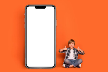 Full body photo of young boy present application show thumb-up select perfect isolated over orange color background