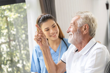 Man being cared for by a private Asian nurse at home suffering from Alzheimer's disease to closely care for elderly patients