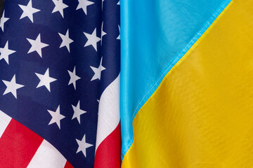 The flag of Ukraine and the flag of America are joined together, close-up, bends and waves on the flags. Concept: joint meeting, lend-lease assistance.