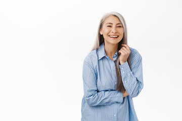 Portrait of beautiful, healthy and happy old korean woman, laughing and smiling, standing over...