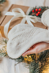 Warm Christmas Socks held in woman hands with gift box on background 