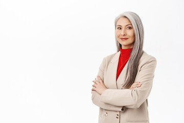 Portrait of professional asian senior businesswoman, cross arms on chest, looking confident, wearing stylish suit, smiling assertive, working in corporate, white background - 510884011