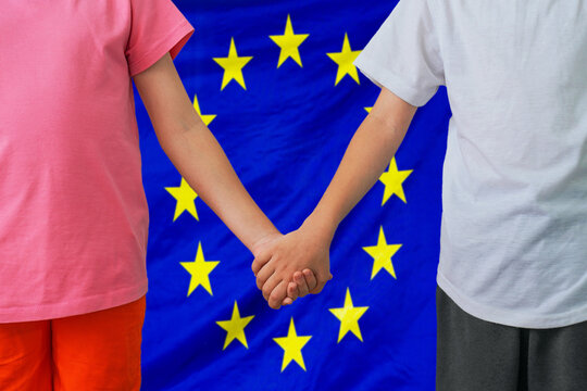 Two children joined hands on flag EU background. Boy and girl joined hands on background flag of EU. Concept of family and parenting in European Union