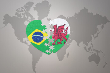 puzzle heart with the national flag of brazil and wales on a world map background.Concept.