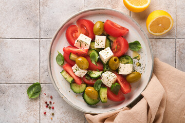 Greek salad. Fresh Greek salad with fresh vegetables, tomato, cucumber, green olives and feta cheese on old grey concrete table background. Top view.