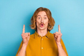 Portrait of attractive stunned long-haired guy demonstrating up copy space isolated over bright...