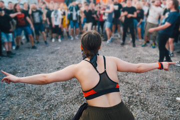 People at summer metal music festival before the mosh pit. Girl with hands raised wide show the...