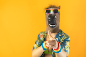 Portrait of lesbian female wearing crazy horse animal mask and LGBTQ+ pride rainbow wristband and...