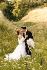 Wedding couple newlyweds tenderly hug and kiss on the background of the hills