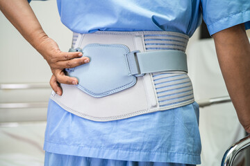 Asian lady patient wearing back pain support belt for orthopedic lumbar with walker.