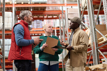African young worker discussing cargo delay with his colleagues during their teamwork in warehouse