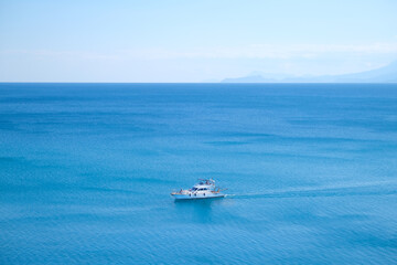 White yacht floats on blue water in the sea against the backdrop of mountains on a sunny day