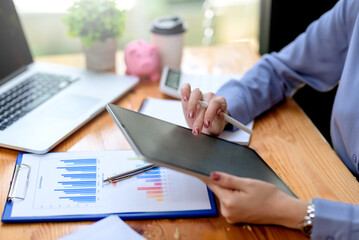 Close-up of business woman using tablet analyzing chart and graph showing changes on the market. Female using digital tablet to send text , work or play social media in office.