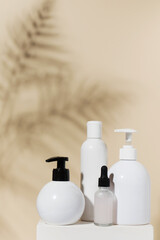 Set of natural cosmetic products on beige background with shadow of palm leaves