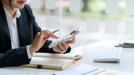 Close up woman accountant using calculator. Business woman calculating monthly expenses, managing budget,  papers, loan documents, invoices.