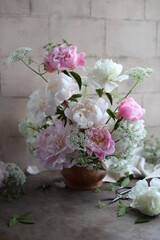 Lush bouquet of white and pink peonies. Floral arrangement of seasonal garden flowers in a wooden bowl. Floral summer still life.