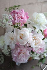Lush bouquet of white and pink peonies. Floral arrangement of seasonal garden flowers in a wooden bowl. Floral summer still life.