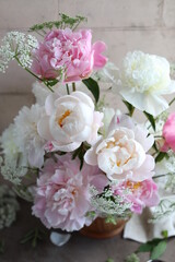 Lush bouquet of white and pink peonies. Floral arrangement of seasonal garden flowers in a wooden bowl. Floral summer still life.