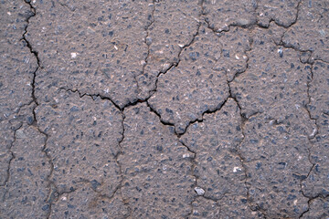 Old worn and cracked asphalt with cracks. Asphalt cracked road dark texture.