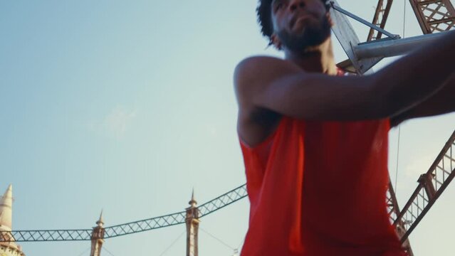 Cinematic footage of a street basketball game outdoor. Basketball players training and having fun at the court doing slam dunks and tricks