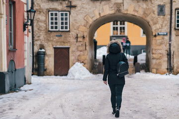 Fototapeta na wymiar Urban portrait of a woman in a coat walking down a snowy street. Street lifestyle and urban environment.