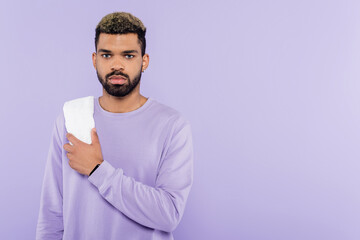 bearded african american man in sweater holding white towel isolated on purple.