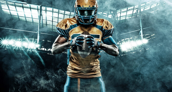 American football player on stadium with ball in hands and helmet on head. Sports background and wallpaper. Black skin athlete.