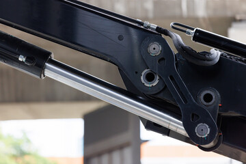 chrome hydraulic cylinder of black crane with concrete sky way as background.