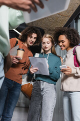low angle view of multiethnic students looking at copybook on blurred foreground.