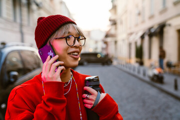 Asian boy laughing and talking on mobile phone at street