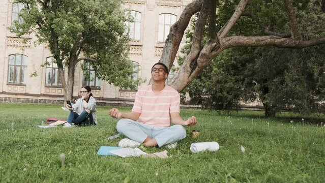 Meditation and relaxation outdoor in the campus. A young mulat male student mediating before exams